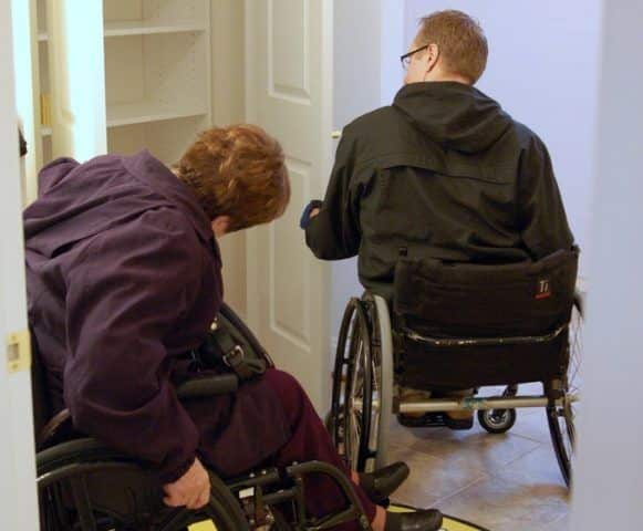 Two people in wheelchairs navigating a doorway, illustrating accessibility in home design.