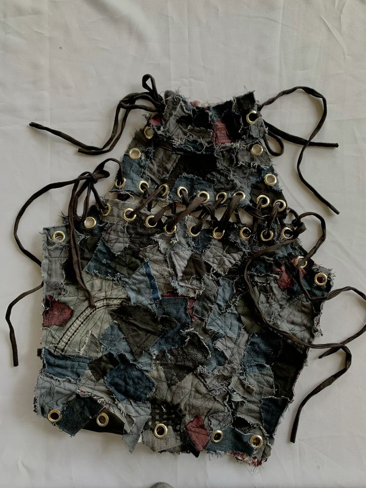 Patchwork denim halter top with laces and grommets, featuring a unique artistic design on a white background.