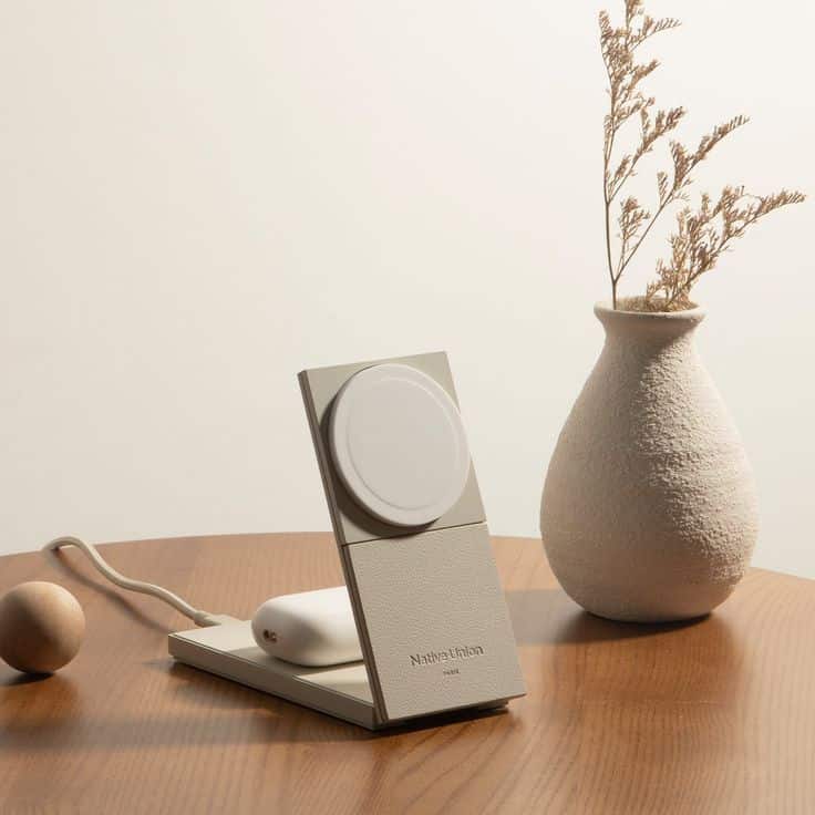 Modern wireless charger on wooden table with decorative beige vase and minimalistic design elements.