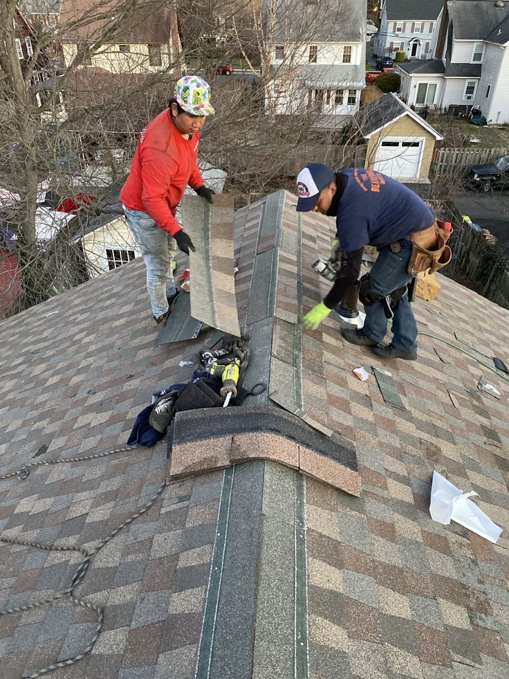 Workers installing shingles on a rooftop, focusing on precision and safety equipment.