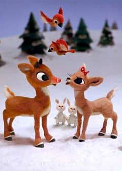 Toy reindeer and birds in snowy forest scene; festive holiday atmosphere with trees and rabbits in the background.