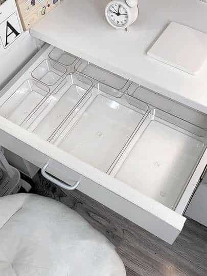 SHEIN Empty desk drawer with clear plastic organizers, white desk, and clock, for minimalist home office organization. | Sky Rye Design Empty desk drawer with clear plastic organizers, white desk, and clock, for minimalist home office organization.