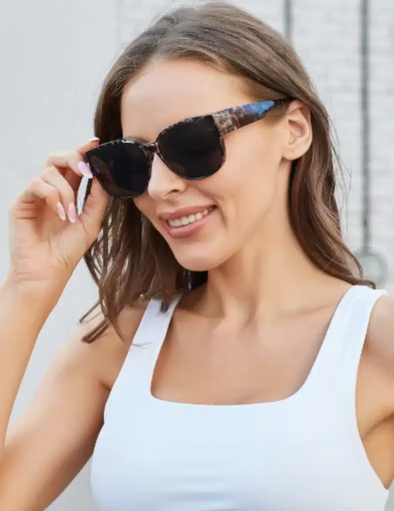 Screenshot_2025-02-13_at_160549 Woman smiling in stylish sunglasses and white top, adjusting frames outdoors. | Sky Rye Design Woman smiling in stylish sunglasses and white top, adjusting frames outdoors.
