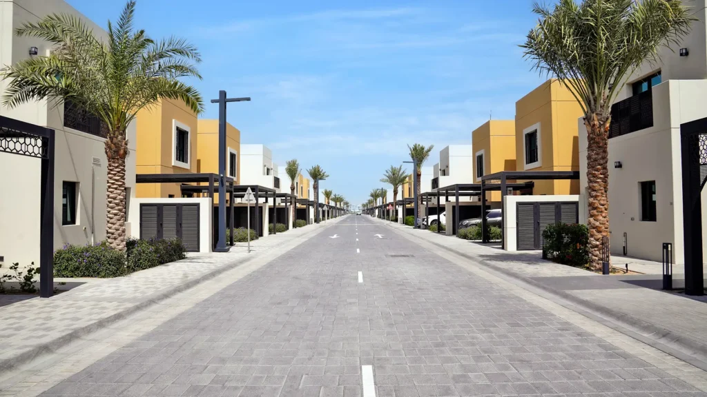 Modern residential street with palm trees and colorful buildings under a clear blue sky.