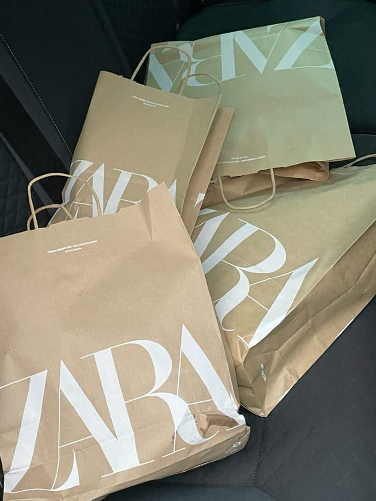 Shopping bags from Zara on a car seat, showcasing a recent fashion haul.