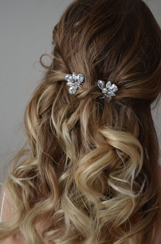 Elegant bridal hairstyle with pearl hairpins and flowing blonde curls.