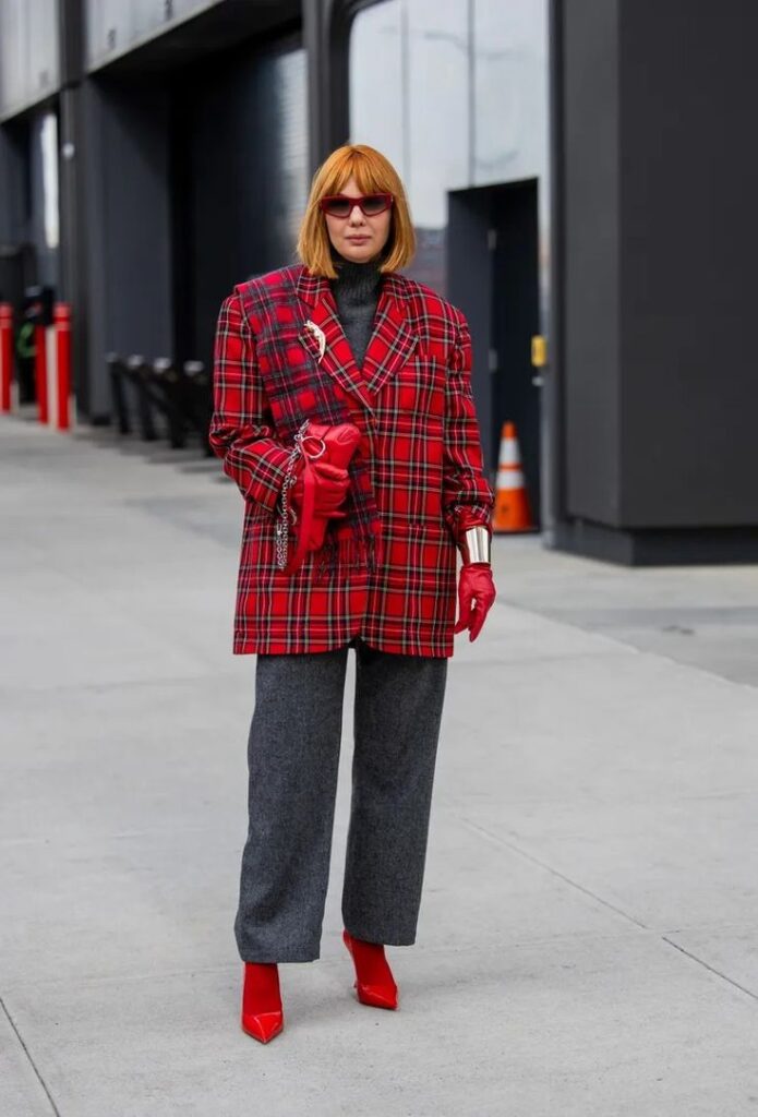 Street Style Is Bringing the Antique Brooch Back Fashionable woman in red plaid blazer, gray pants, red gloves, and boots, standing confidently on a city street. | Sky Rye Design Fashionable woman in red plaid blazer, gray pants, red gloves, and boots, standing confidently on a city street.