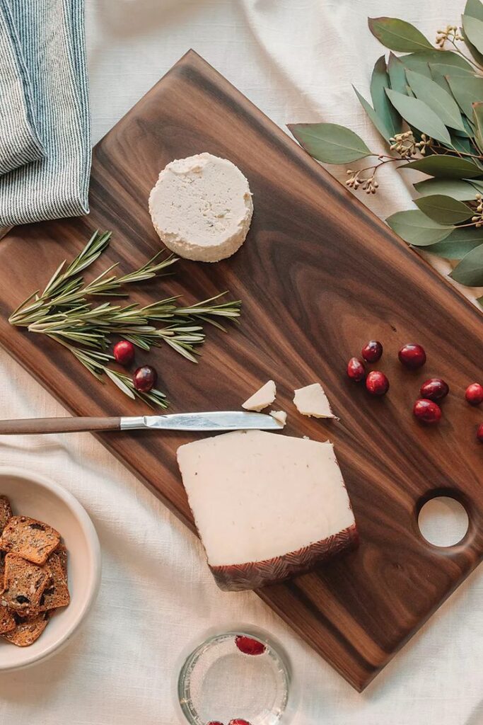 Sunhouse Craft Walnut Serving Board Cheese platter with rosemary, cranberries, and crackers on a wooden board for a cozy table setting. | Sky Rye Design Cheese platter with rosemary, cranberries, and crackers on a wooden board for a cozy table setting.