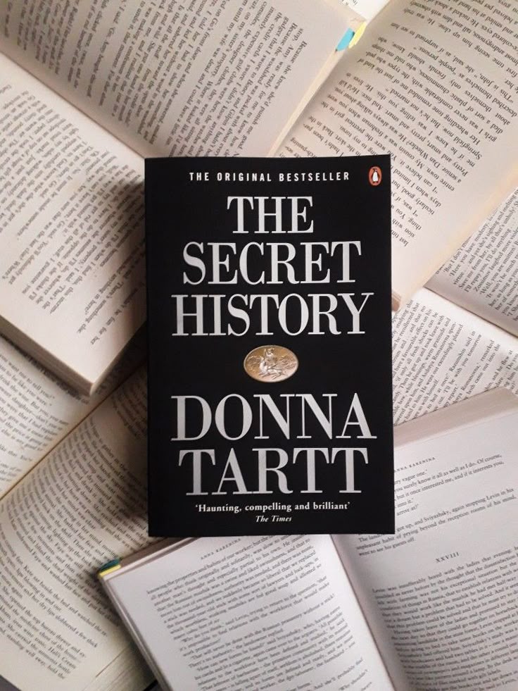 The Secret History by Donna Tartt The Secret History book by Donna Tartt on background of open books, original bestseller cover. | Sky Rye Design The Secret History book by Donna Tartt on background of open books, original bestseller cover.