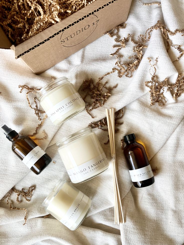 The Ultimate Gift Set Assorted scented candles and oils from Studio 17 on a textured fabric with decorative packaging accents. | Sky Rye Design Assorted scented candles and oils from Studio 17 on a textured fabric with decorative packaging accents.