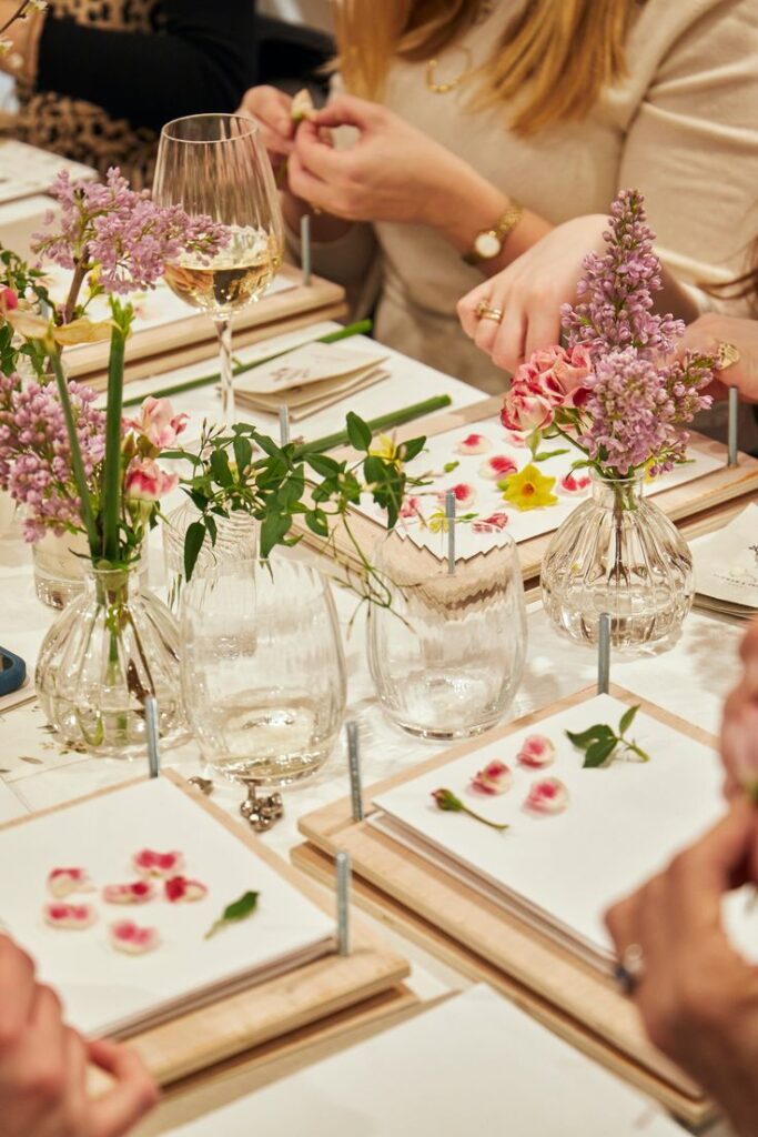 The White Company Events 2024 Flower pressing workshop with fresh blooms, craft materials, and wine on a table. Perfect for creative gatherings. | Sky Rye Design Flower pressing workshop with fresh blooms, craft materials, and wine on a table. Perfect for creative gatherings.