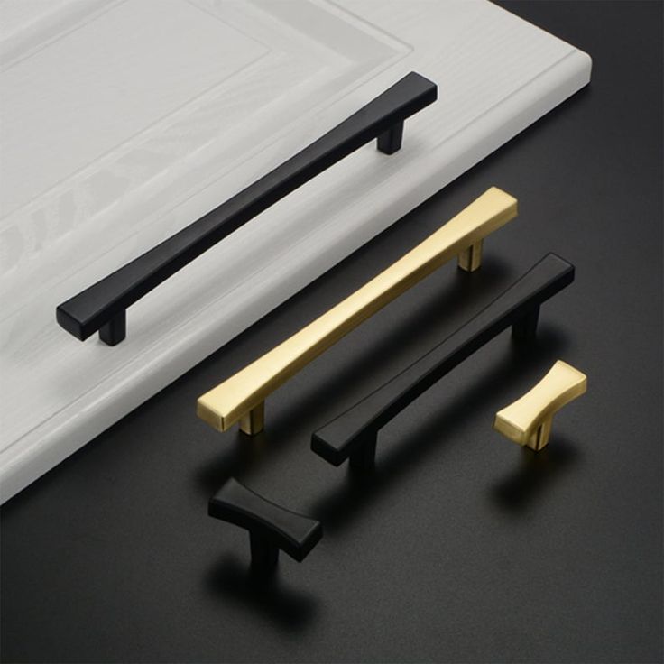 Black and gold cabinet handles displayed on a white surface, perfect for modern kitchen or home decor.