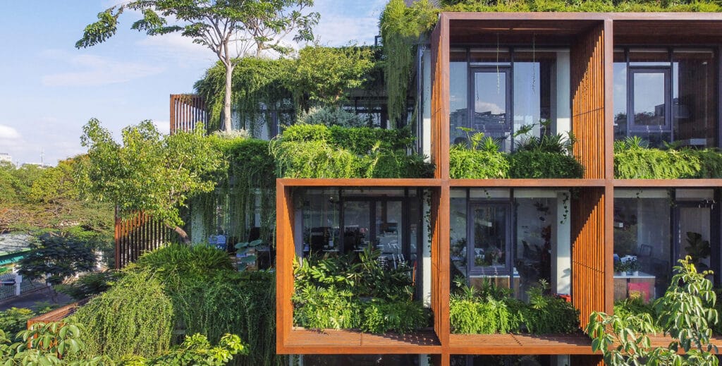 Tony-Fruit-Office-Ho-Chi-Minh-City-Vietnam-by-TAA-Design-AAwards-Jury-Winner-in-the-Low-Rise-Office-category-photo-by-Hoang-Le_for-site Modern building with lush green plants on balconies, showcasing eco-friendly urban architecture. | Sky Rye Design Modern building with lush green plants on balconies, showcasing eco-friendly urban architecture.