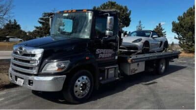 Tow truck transporting a sports car on a sunny day, providing reliable roadside assistance.