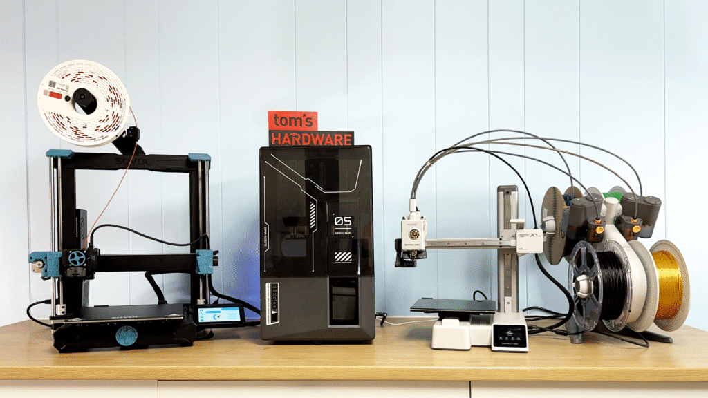 Variety of 3D printers and filament spools in a tech workshop on a wooden table.