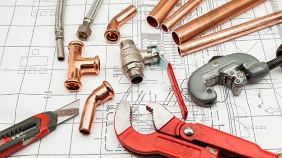 Use Smarter Plumbing Solutions to Improve Home Renovation Plumbing tools and copper pipes arranged on blueprint for home construction or repair project. | Sky Rye Design Plumbing tools and copper pipes arranged on blueprint for home construction or repair project.