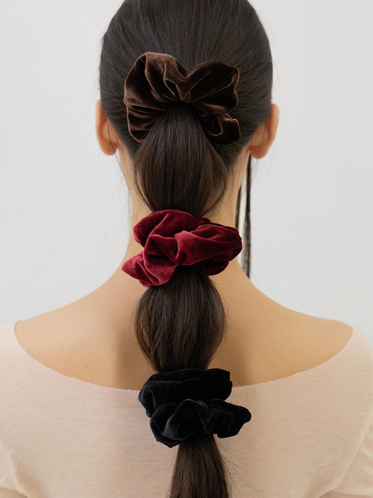 Woman's long ponytail with brown, red, black velvet scrunchies, stylish hair accessories.