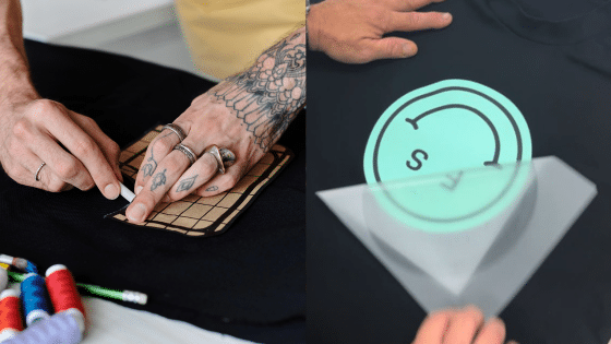 Tattooed hands applying custom designs on black t-shirts.