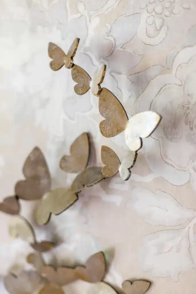 WarmSilverButterflyCloseUp Metallic butterfly wall art on floral-patterned wallpaper, enhancing home decor with nature-inspired design. | Sky Rye Design Metallic butterfly wall art on floral-patterned wallpaper, enhancing home decor with nature-inspired design.