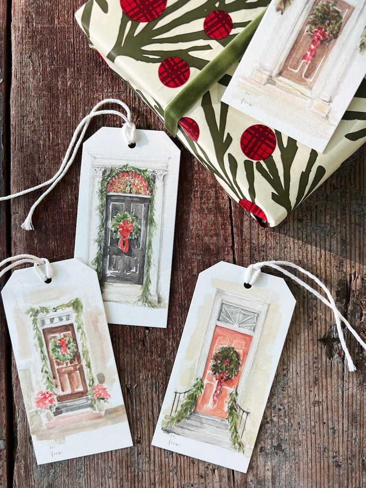 Gift tags with festive door illustrations next to wrapped present on wooden surface.