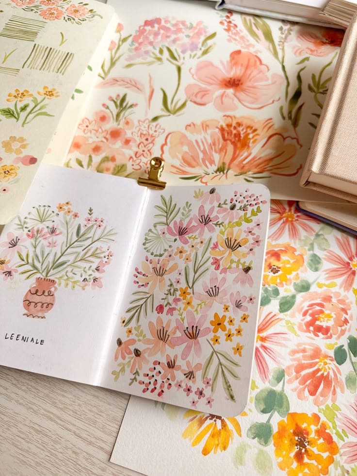Floral watercolor illustrations in a sketchbook with vibrant pink, orange, and yellow flowers.