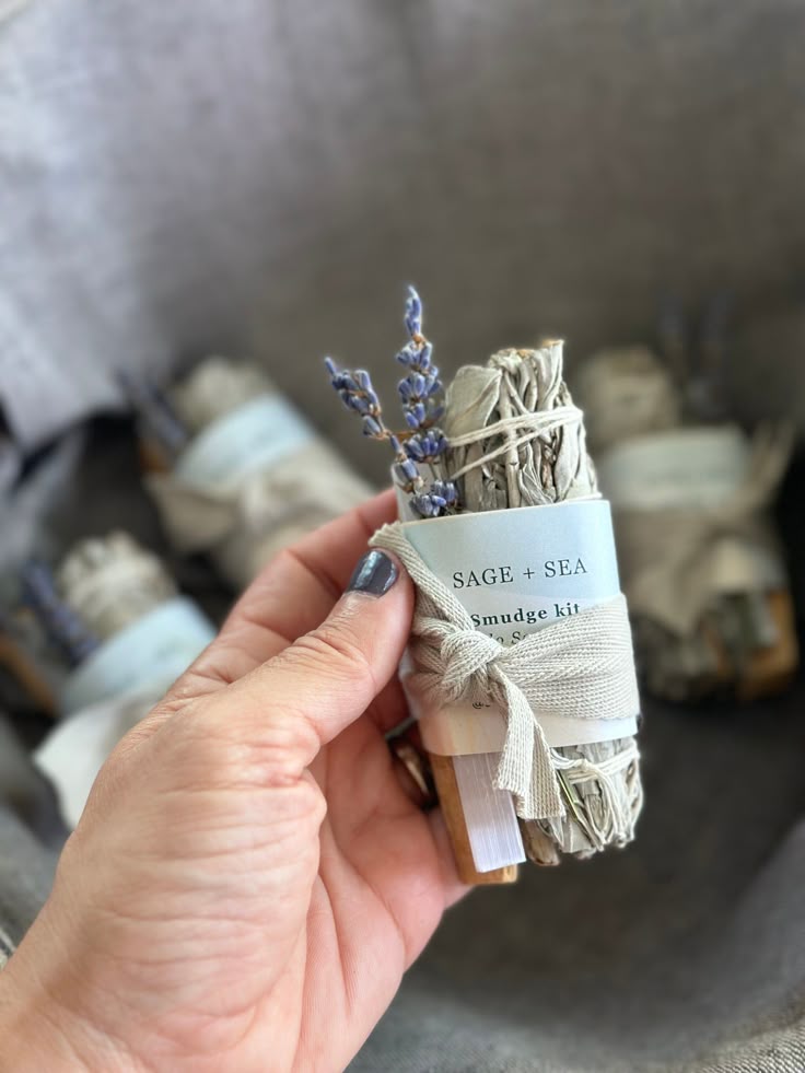 Hand holding a Sage + Sea smudge kit with sage and dried lavender, perfect for cleansing and aromatherapy rituals.