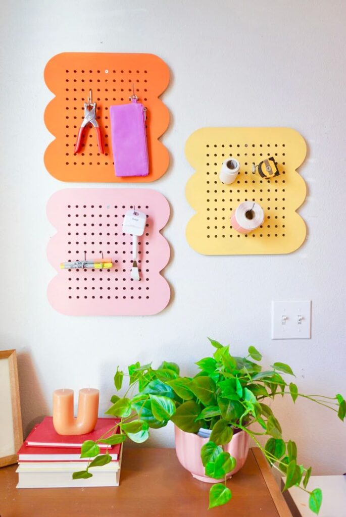 Colorful DIY pegboards on a wall above a desk with books and a potted plant.