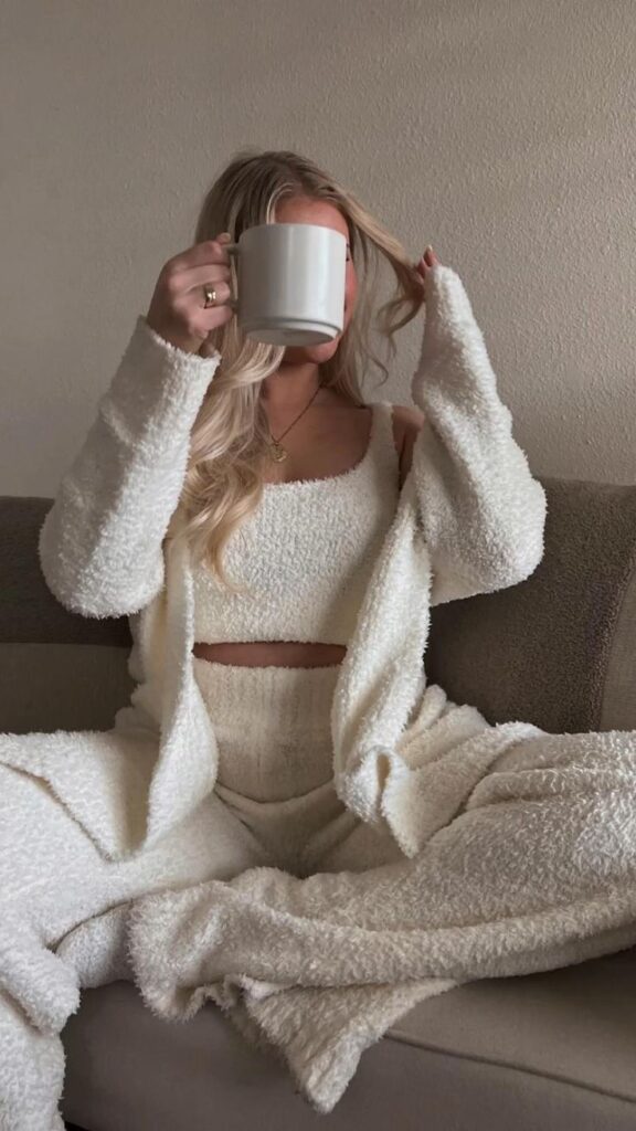 a3277aa0-f94c-4f27-bd67-0d2397b016e1 Cozy moment: Woman in fluffy loungewear sipping coffee on sofa, embracing a relaxed morning vibe. | Sky Rye Design Cozy moment: Woman in fluffy loungewear sipping coffee on sofa, embracing a relaxed morning vibe.