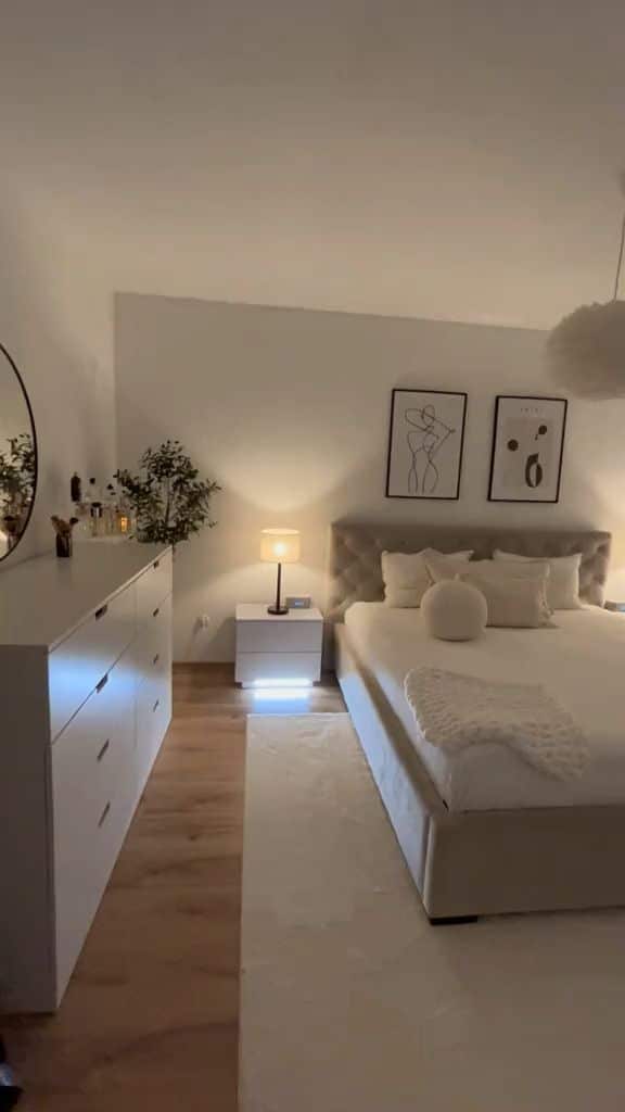 a8b9937b-1c42-445b-8c6e-fbb590e8c6fd Modern bedroom with cozy lighting, artwork, dresser, and neatly made bed. Stylish and minimalist decor. | Sky Rye Design Modern bedroom with cozy lighting, artwork, dresser, and neatly made bed. Stylish and minimalist decor.