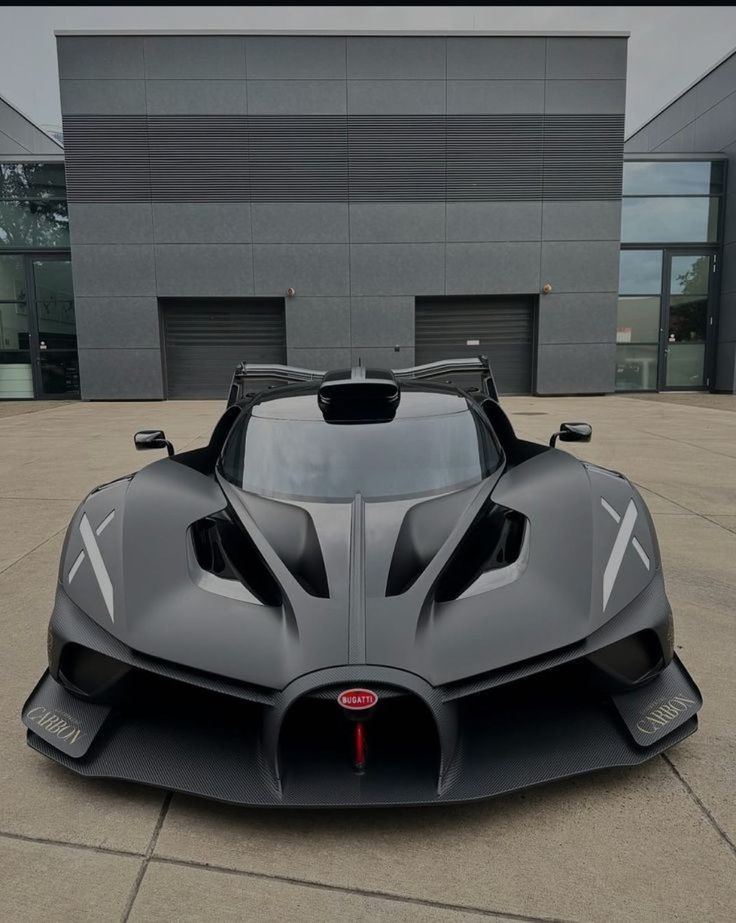 Sleek black Bugatti supercar parked in front of a modern building, showcasing aerodynamic design and luxury performance.