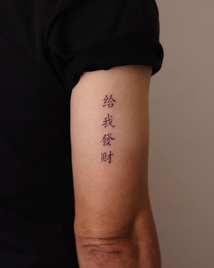 ad99085a-8d8f-44ef-a8ae-379030979d0c Arm tattoo with Chinese characters on a person wearing a black shirt. | Sky Rye Design Arm tattoo with Chinese characters on a person wearing a black shirt.