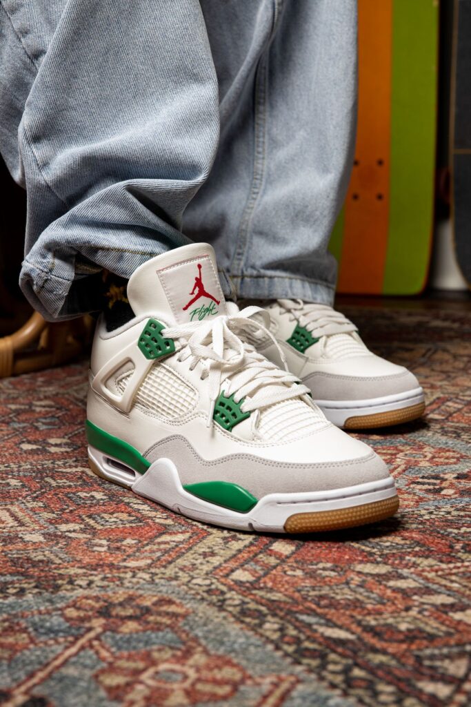 Retro sneakers with green accents on patterned rug, worn with light blue jeans. Perfect for casual street style.