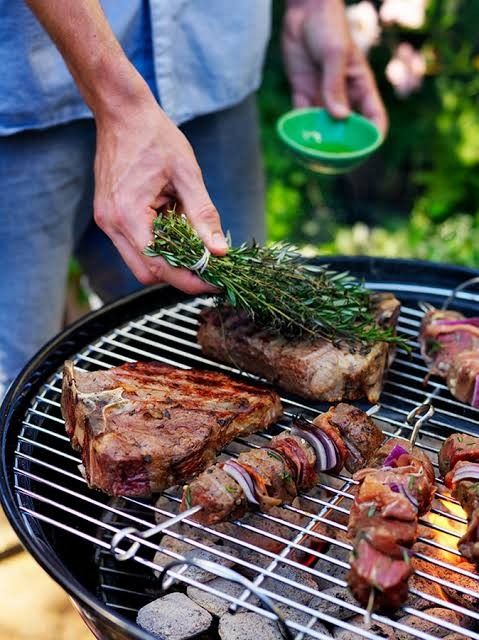 Grilling meat with fresh herbs on a barbecue, featuring juicy steaks and skewers for a delicious outdoor cookout.