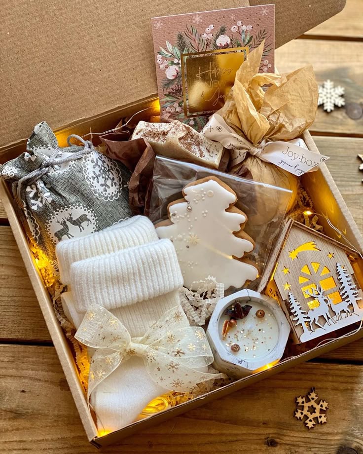 Festive gift box with holiday treats, cozy socks, and decorative items on a wooden table, perfect for Christmas.