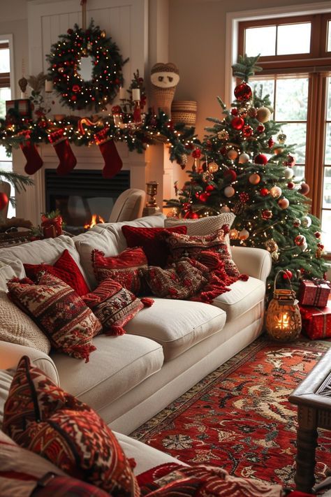 Cozy Christmas living room with festive decor, a lit fireplace, Christmas tree, and red cushions on a white sofa.