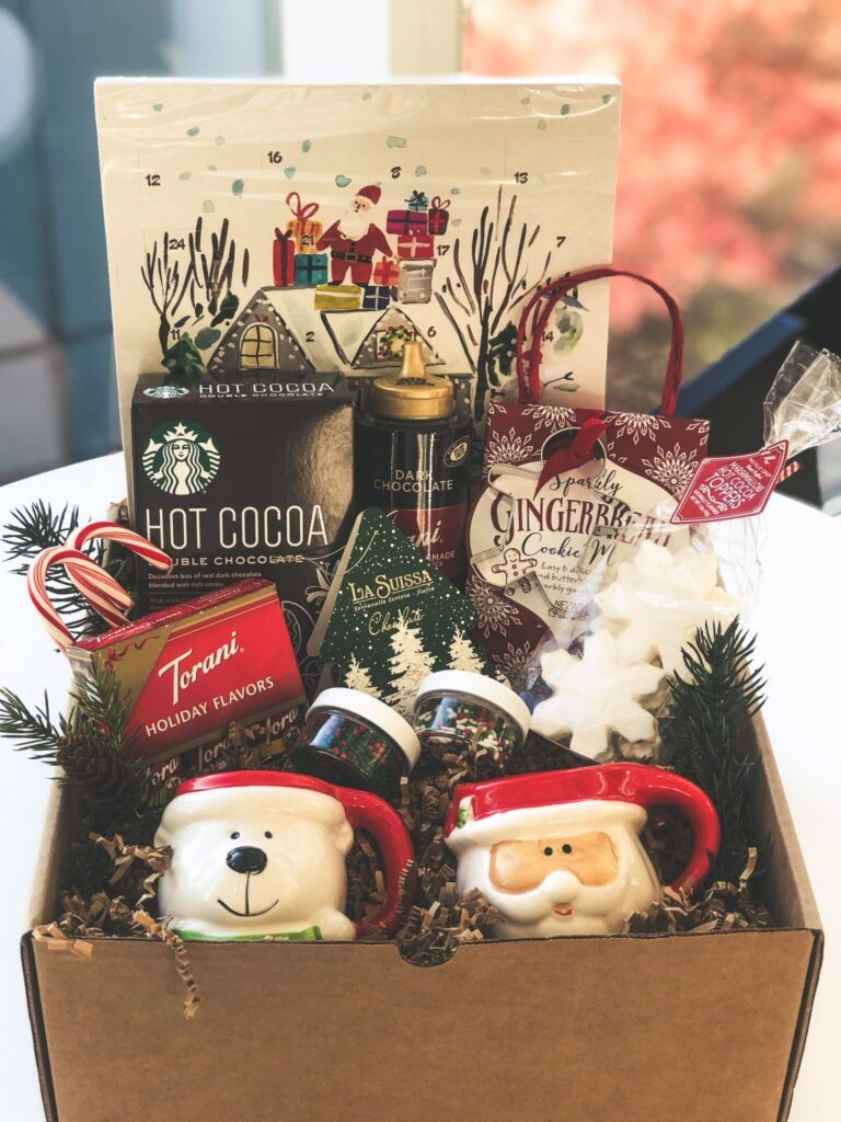 Festive holiday gift box with hot cocoa, gingerbread mix, seasonal mugs, and holiday treats for a cozy winter season.