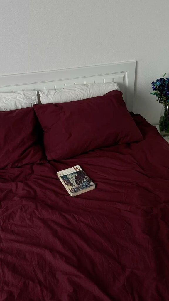 bordo bed Cozy bedroom with burgundy bedding and a book on the bed, next to a vase of purple flowers. | Sky Rye Design Cozy bedroom with burgundy bedding and a book on the bed, next to a vase of purple flowers.