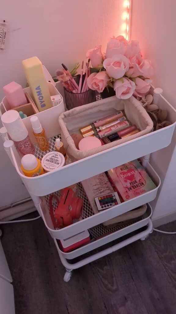 c0a88783-dc13-4410-9a32-404dcf4db551 Vanity cart with makeup, skincare products, pink roses, and accessories in soft lighting. | Sky Rye Design Vanity cart with makeup, skincare products, pink roses, and accessories in soft lighting.