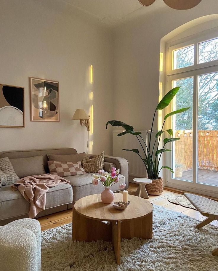 Cozy living room with beige sofa, wooden coffee table, large plant, and modern decor in natural light.