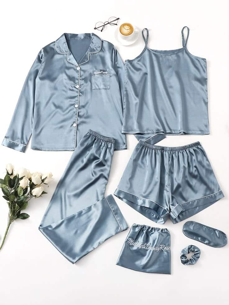 Silk blue pajama set with top, shorts, pants, eye mask, and scrunchie, styled with flowers and coffee.