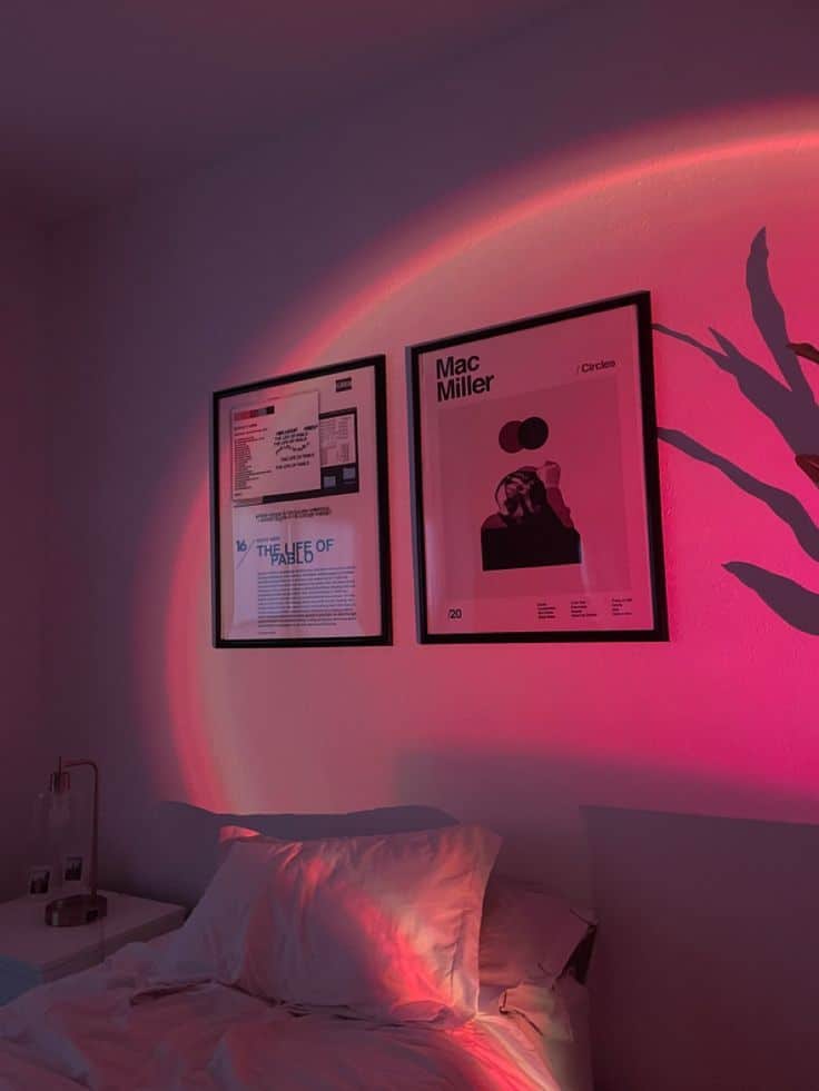 Cozy bedroom with art on walls, pink ambient light, and soft pillows. Modern interior design inspiration.