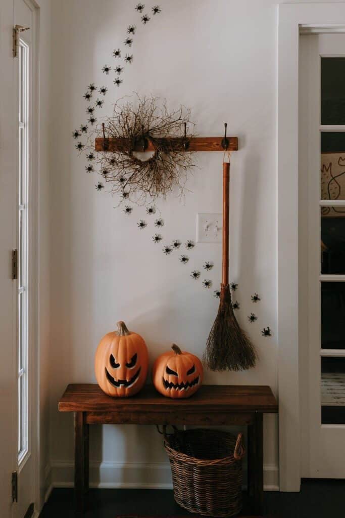 c5ebfd4ab3347d405db8712cc6354325 Halloween decorations with jack-o'-lanterns, broom, spiders, and a vine wreath on a wooden table. | Sky Rye Design Halloween decorations with jack-o'-lanterns, broom, spiders, and a vine wreath on a wooden table.