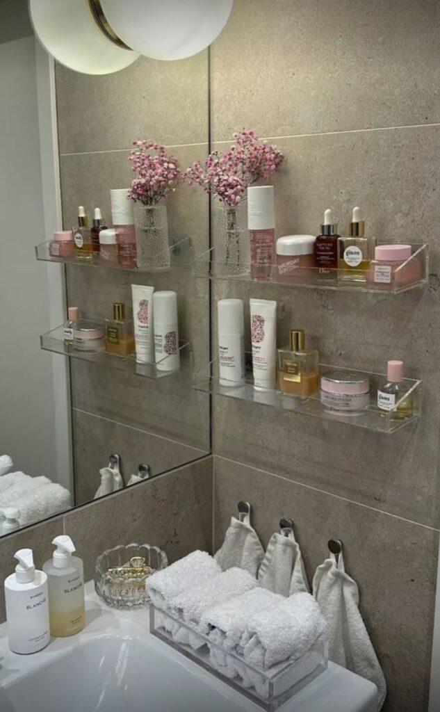 c65ba224-5c20-4339-81cc-8398dd40be2c Chic bathroom with skincare products, fresh flowers, and neatly arranged towels on display shelves. | Sky Rye Design Chic bathroom with skincare products, fresh flowers, and neatly arranged towels on display shelves.