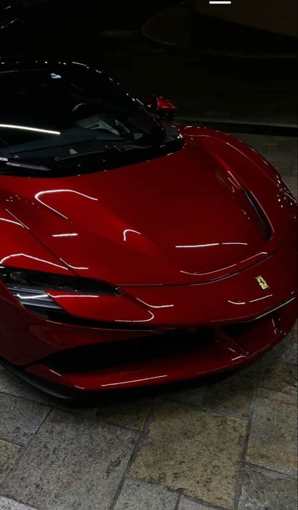 Red sports car with sleek design and glossy finish, parked on a tiled floor, showcasing luxury and performance.