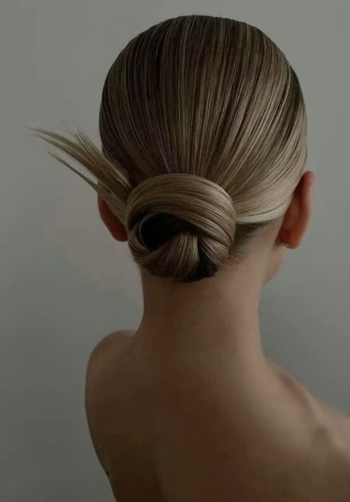 Elegant blonde hair in a sleek low bun, showcasing a modern and sophisticated hairstyle.