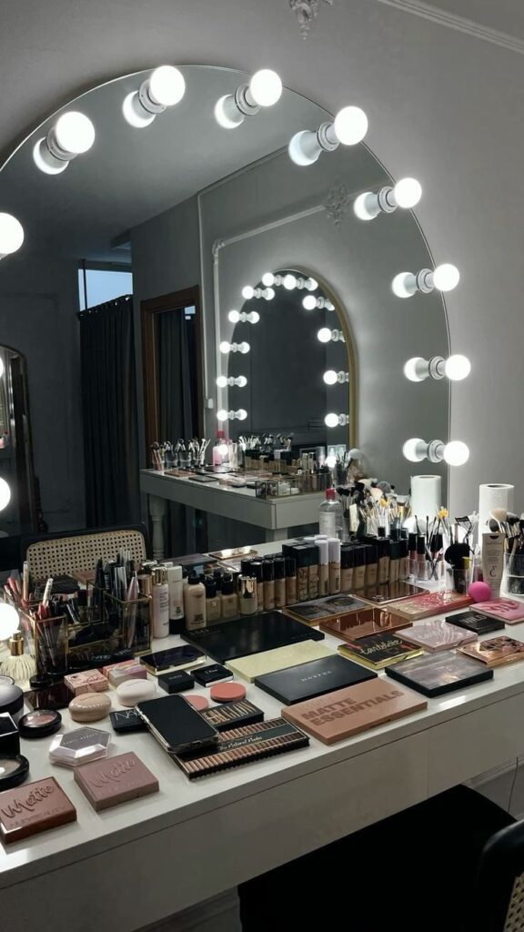 cd91e817-614f-4cb1-9894-877488db53c1 Makeup vanity with illuminated mirror and cosmetics neatly arranged on the table, ready for a beauty routine. | Sky Rye Design Makeup vanity with illuminated mirror and cosmetics neatly arranged on the table, ready for a beauty routine.