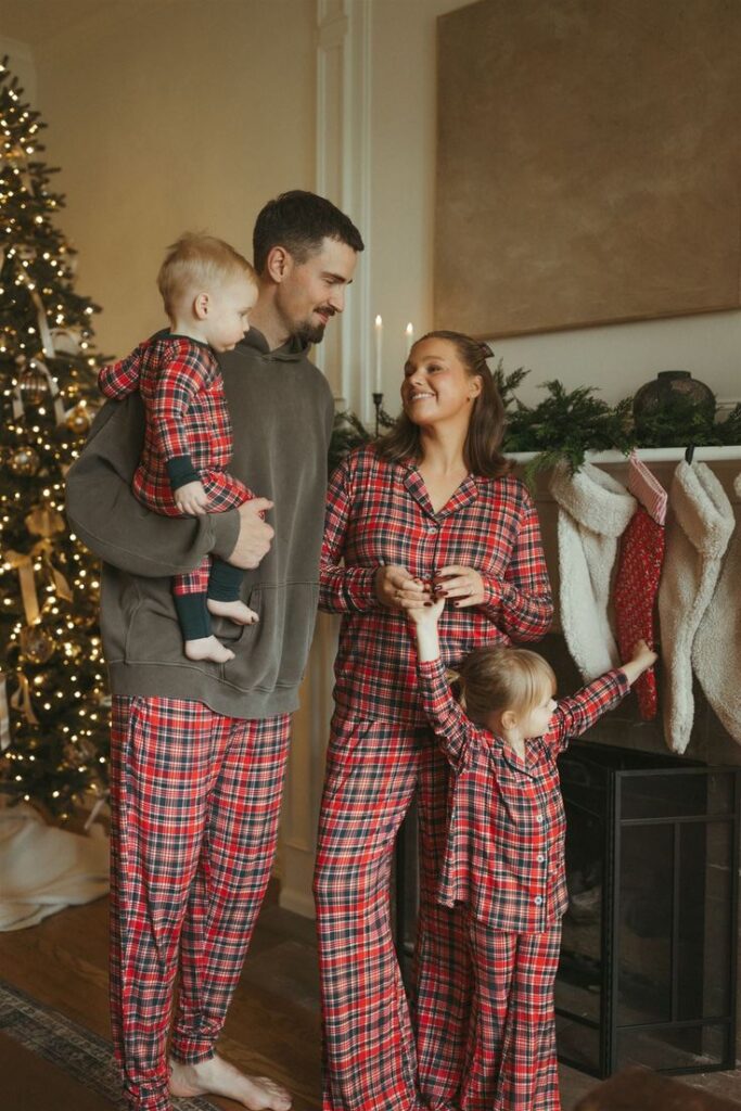 ce5d2e40-46ce-4100-9636-9322d2308363 Family in matching plaid pajamas celebrating Christmas by the tree and stockings. | Sky Rye Design Family in matching plaid pajamas celebrating Christmas by the tree and stockings.