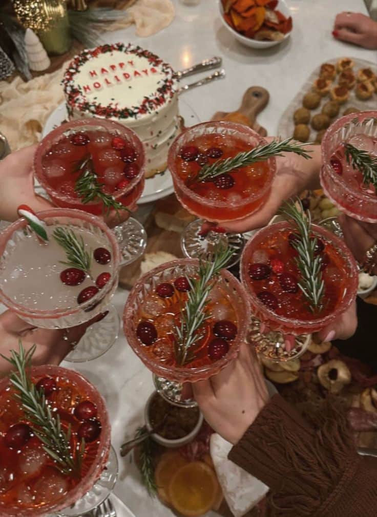 Festive holiday toast with cranberry cocktails, rosemary, and a decorated cake; vibrant and celebratory atmosphere.