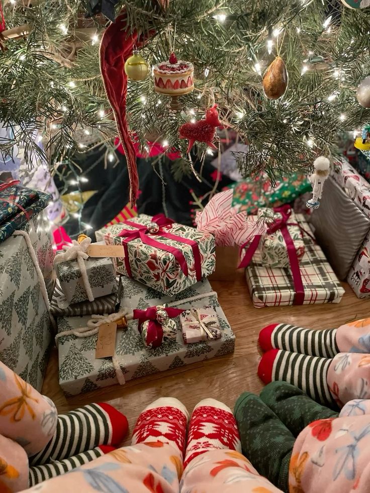 Cozy Christmas scene with festive socks, gifts, and twinkling tree lights under a decorated tree.