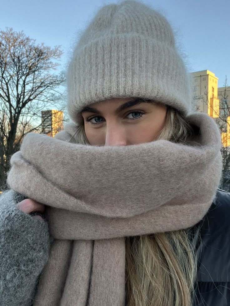 Woman in cozy winter hat and scarf outdoors on a clear day, keeping warm.